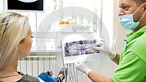 Young blonde woman looking at x-ray image of her teth in dentist office