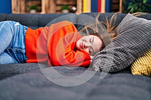 Young blonde woman lying on sofa sleeping at home