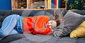 Young blonde woman lying on sofa sleeping at home