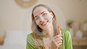 Young blonde woman make up lips smiling at bedroom