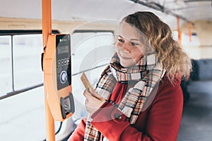 Young blonde woman making payment of public transport ticket fare at automatic contactless machine with a card