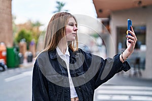 Young blonde woman making selfie by the smartphone at street