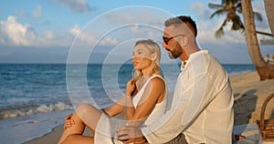 Young blonde woman and man in white shirt dating on evening beach, enjoying summer time