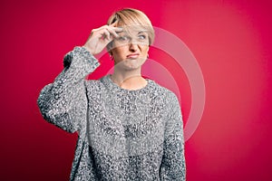 Young blonde woman with modern short hair wearing casual sweater over pink background worried and stressed about a problem with