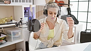 Young blonde woman musician composing song singing at music studio
