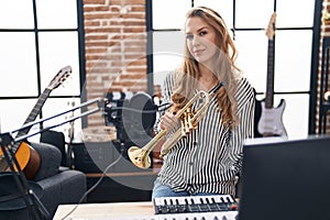 Young blonde woman musician holding trumpet at music studio