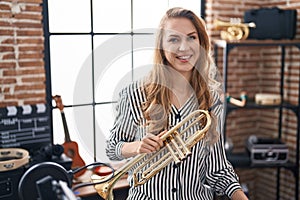 Young blonde woman musician holding trumpet at music studio