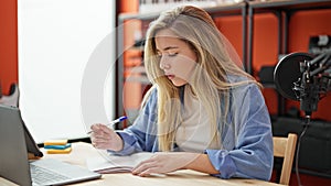 Young blonde woman musician writing song at music studio