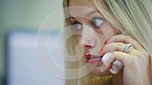 Young Blonde Woman in office talking on phone in front of the computer, extremely close up