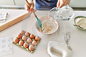 Young blonde woman pouring water on bowl at kitchen