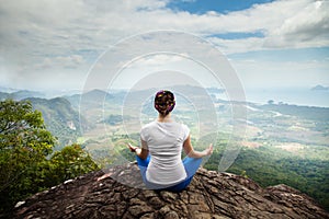 Young blonde woman practicing yoga and meditation in mountains during luxury yoga retreat in Bali, Asia