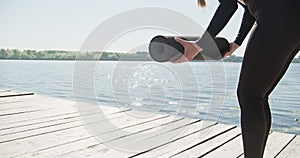 Young Blonde Woman practicing yoga on the wooden berth at lake. Single sport healthy training on nature at sunny weather