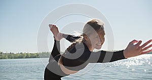 Young Blonde Woman practicing yoga on the wooden berth at lake. Single sport healthy training on nature at sunny weather