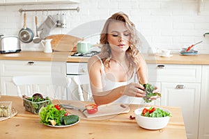 Young blonde woman preparing vegetable salad in her kitchen. Healthy lifestyle, diet and healthy eating concept