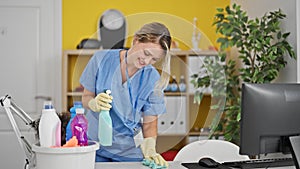 Young blonde woman professional cleaner cleaning table smiling at the office