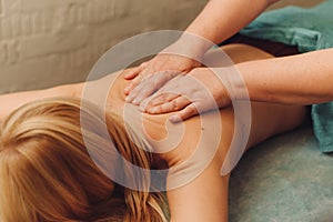 Young blonde woman receiving a back massage in a medical center. Female patient is receiving treatment by professional