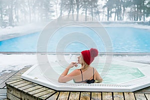 Young blonde woman in red hut in bathtub jacuzzi outdoors at winter