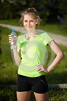 Young blonde woman runner holds blue bottle
