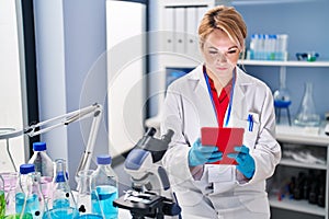 Young blonde woman scientist using touchpad at laboratory