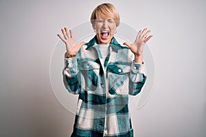 Young blonde woman with short hair wearing casual retro green shirt over  background celebrating mad and crazy for success