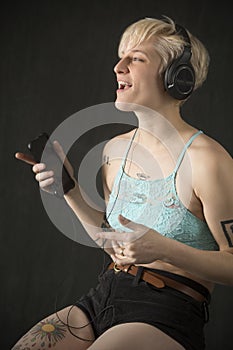 Young blonde woman in shorts, singing with headphones on.