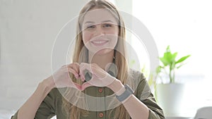 Young Blonde Woman showing Heart with Hands