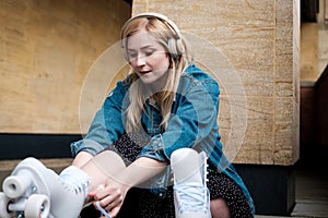 Young blonde woman sitting on the floor tying shoe laces on her roller skate