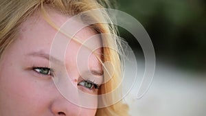 Young blonde woman sitting outdoors