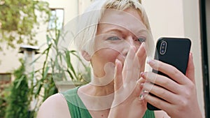 Young Blonde Woman Sitting Outside and Using Phone