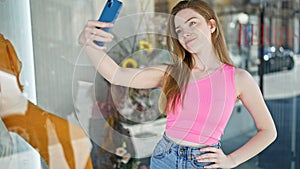 Young blonde woman smiling confident making selfie by the smartphone at clothing store
