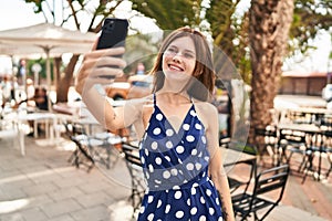 Young blonde woman smiling confident making selfie by the smartphone at coffee shop terrace