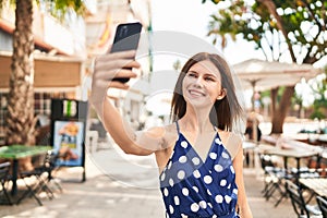 Young blonde woman smiling confident making selfie by the smartphone at coffee shop terrace