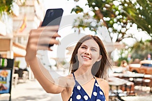 Young blonde woman smiling confident making selfie by the smartphone at coffee shop terrace