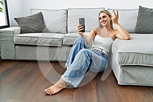 Young blonde woman smiling confident making selfie by the smartphone at home