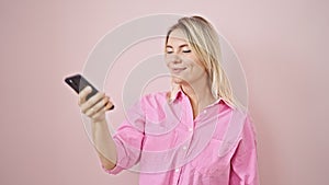 Young blonde woman smiling confident making selfie by the smartphone over isolated pink background