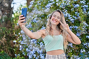 Young blonde woman smiling confident making selfie by the smartphone at park