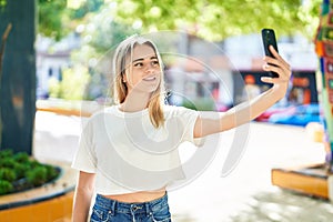 Young blonde woman smiling confident making selfie by the smartphone at park