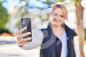 Young blonde woman smiling confident making selfie by the smartphone at park