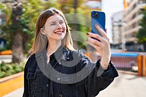 Young blonde woman smiling confident making selfie by the smartphone at park