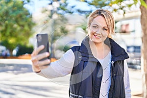 Young blonde woman smiling confident making selfie by the smartphone at park