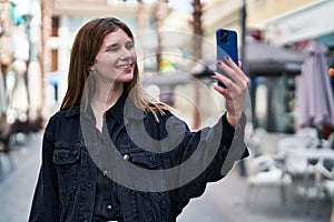 Young blonde woman smiling confident making selfie by the smartphone at street