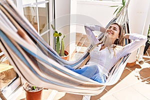 Young blonde woman smiling happy lying on hammock at terrace