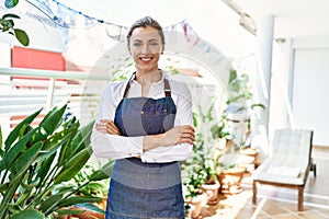 Young blonde woman smiling happy standing with arms crossed gesture at home terrace garden