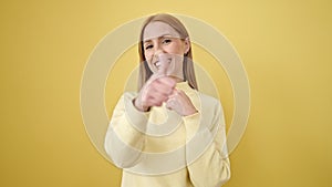 Young blonde woman smiling with thumbs up over isolated yellow background