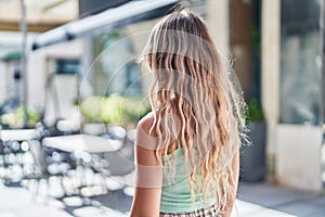 Young blonde woman standing on back view at street