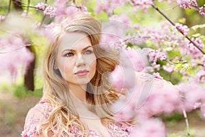 Young blonde woman standing in a blooming garden