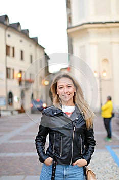 Young blonde woman standing in city and wearing leather jacket, Paris.