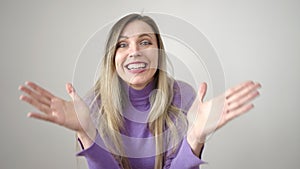Young blonde woman standing with surprise expression over isolated white background