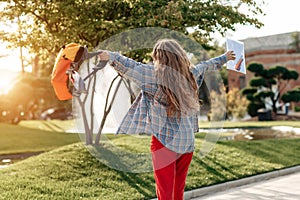 Young blonde woman student celebrate success after exams in university. Back View.