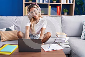 Young blonde woman student sitting on sofa studying at home